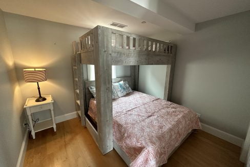 a bedroom with a bunk bed with a pink bedspread.