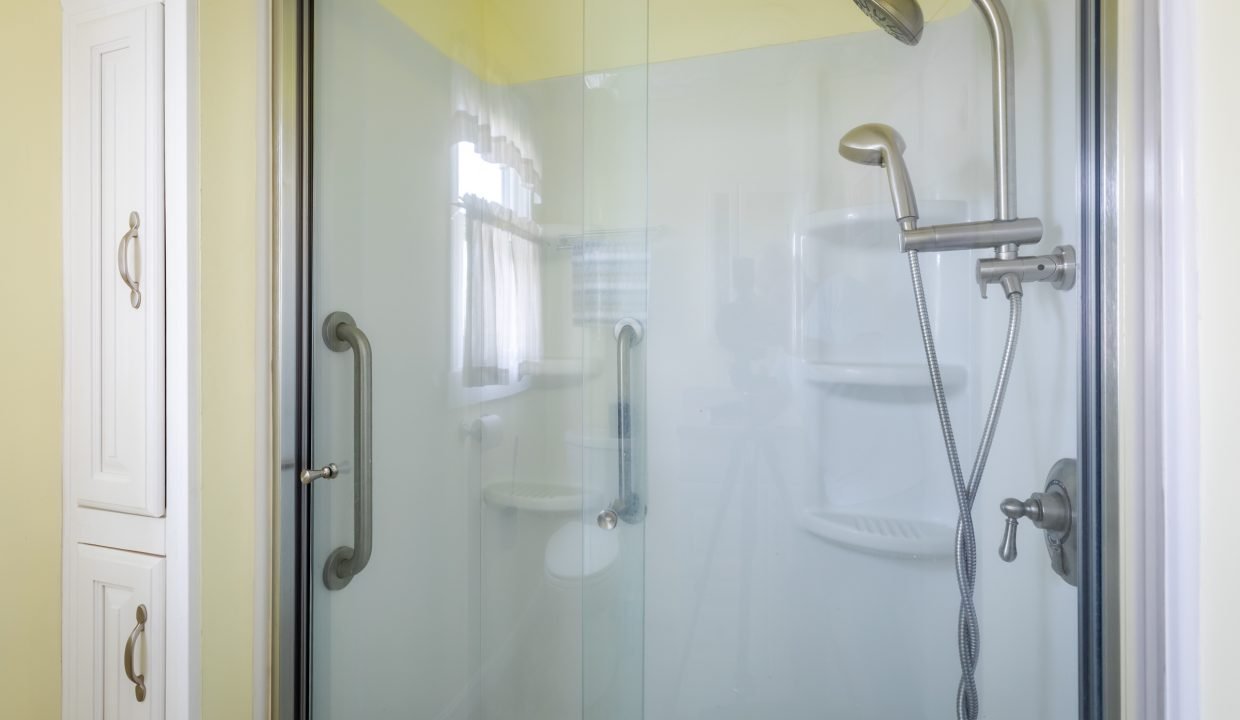 a shower with a glass door and a shower head.