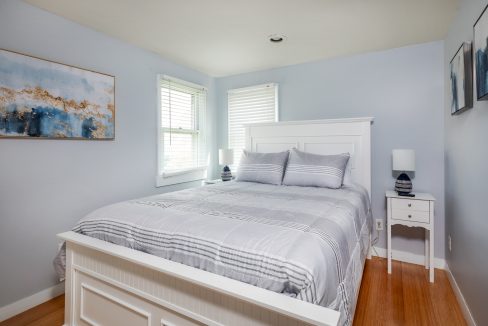 a bedroom with a white bed and a painting on the wall.