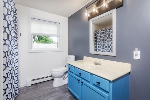 A bathroom with blue cabinets and a white toilet.