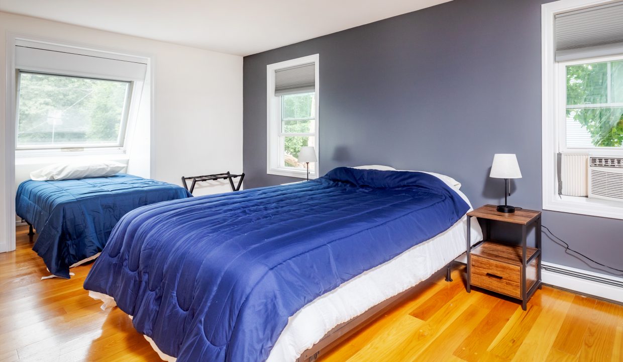 A bedroom with two beds and a blue comforter.