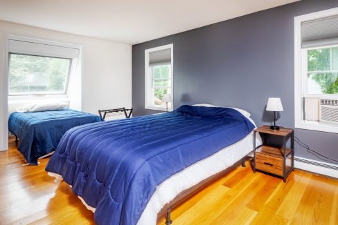 A bedroom with two beds and a blue comforter.