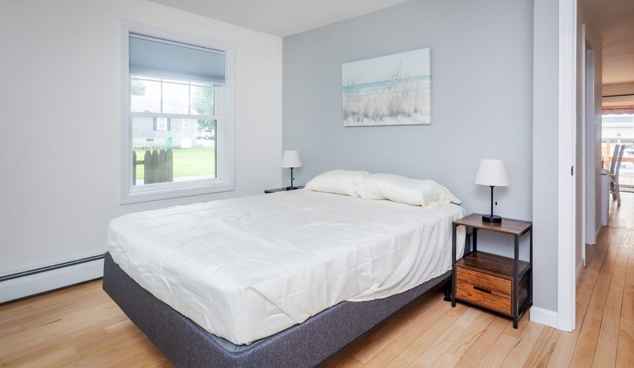 A bedroom with hardwood floors and a bed.