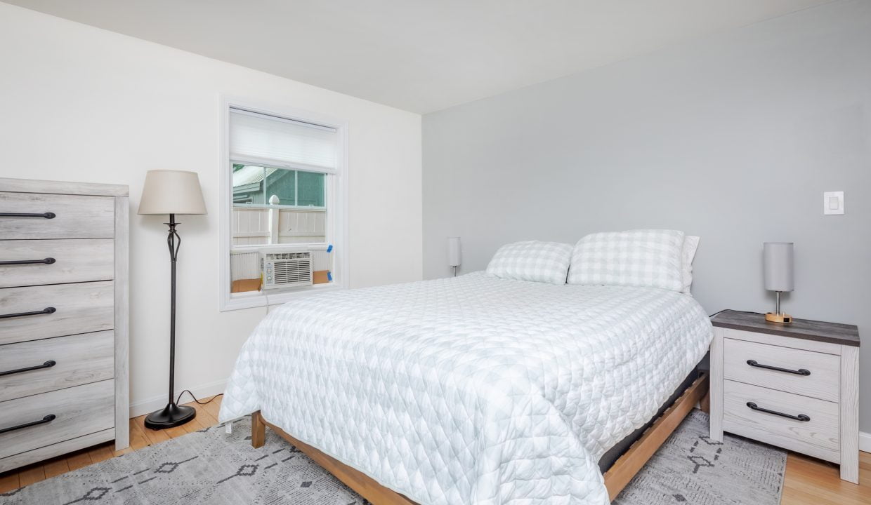 A bedroom with a bed, dresser, and window.