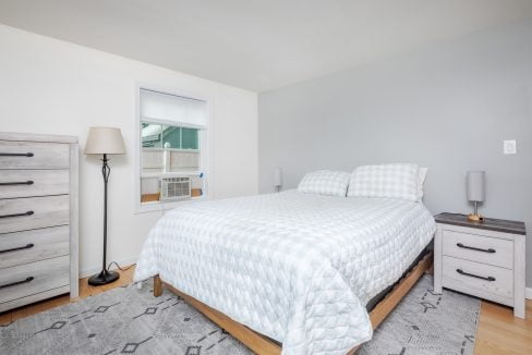 A bedroom with a bed, dresser, and window.