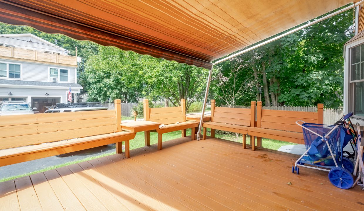A wooden deck with a bench and chairs.