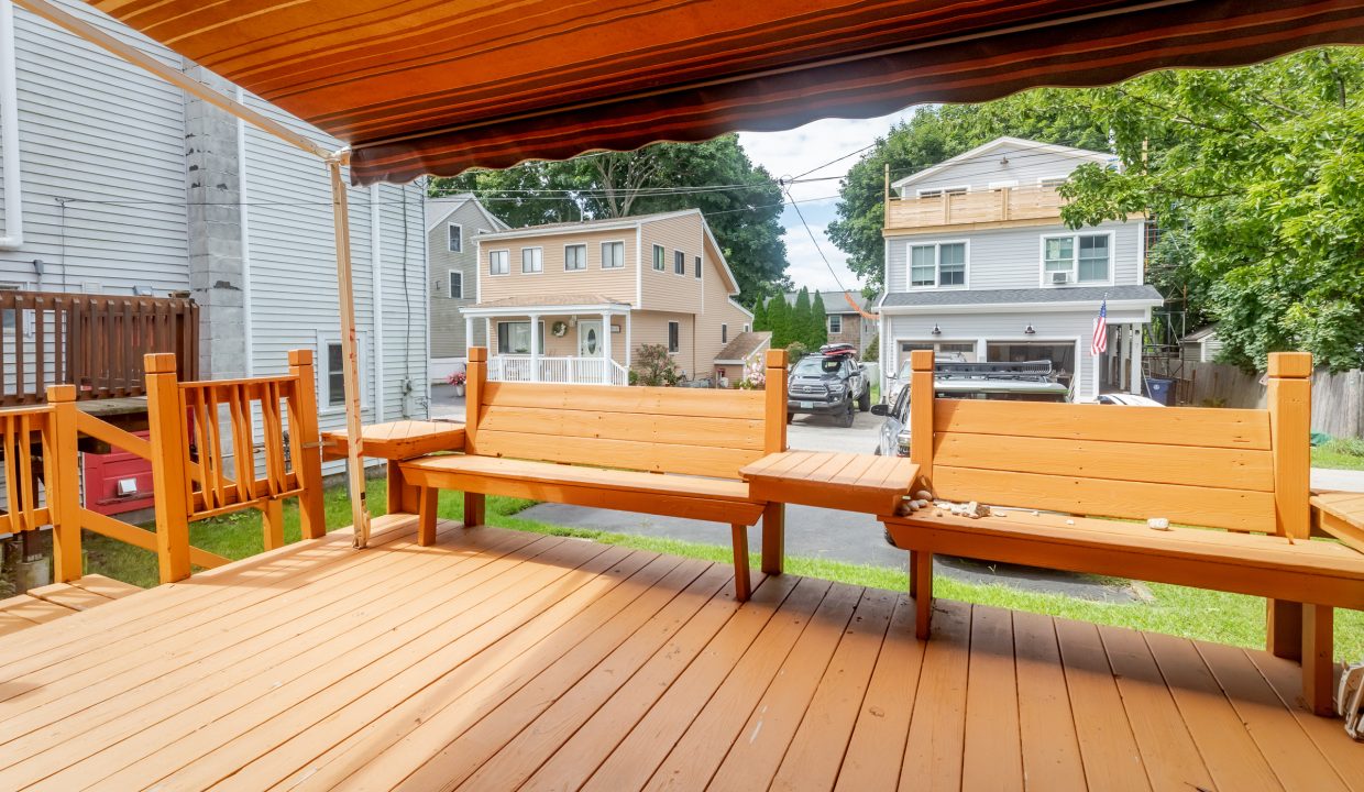 A wooden deck with a bench and awning.