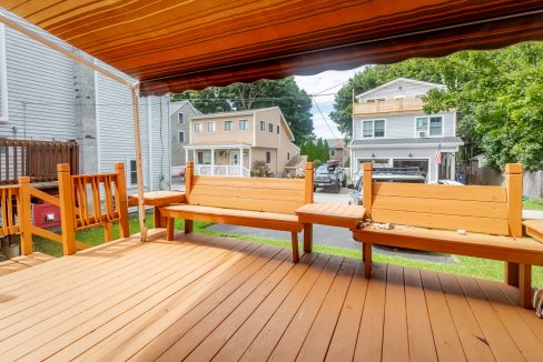A wooden deck with a bench and awning.