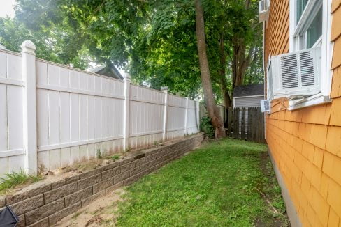 A backyard with a white fence and a tree.