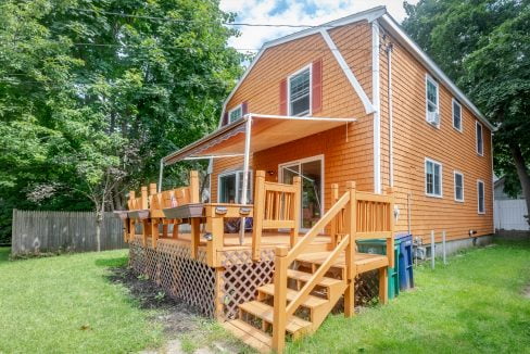 An orange house with a wooden deck and stairs.