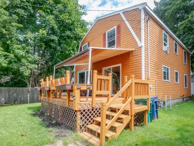 An orange house with a wooden deck and stairs.