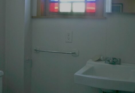 A bathroom with a toilet, sink, and window.