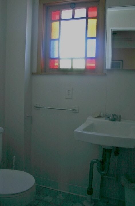 A bathroom with a toilet, sink, and window.