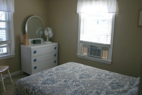 A small bedroom with a bed and a dresser.