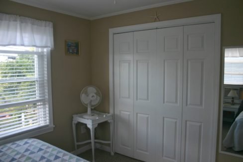 A bedroom with a window and a fan.