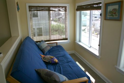 A blue futon in a room with a window.