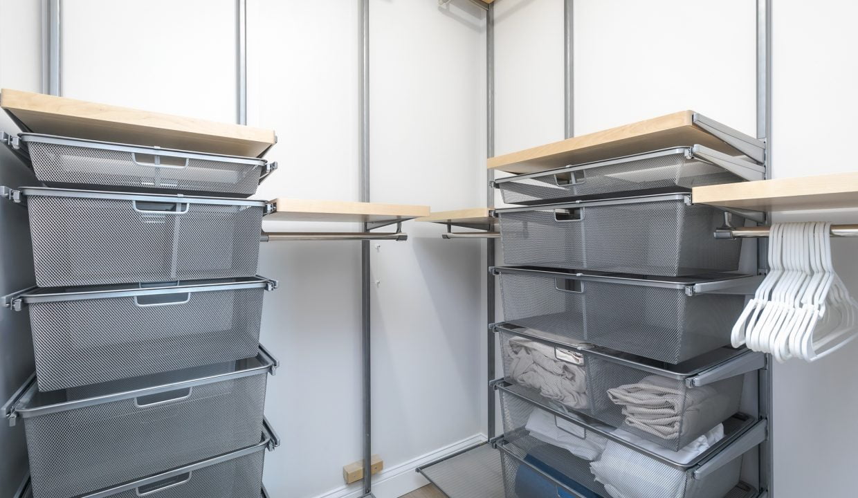 A walk in closet with bins and shelves.