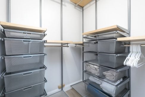 A walk in closet with bins and shelves.