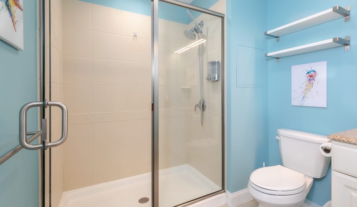 A bathroom with blue walls and a shower stall.