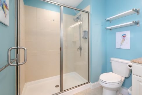 A bathroom with blue walls and a shower stall.