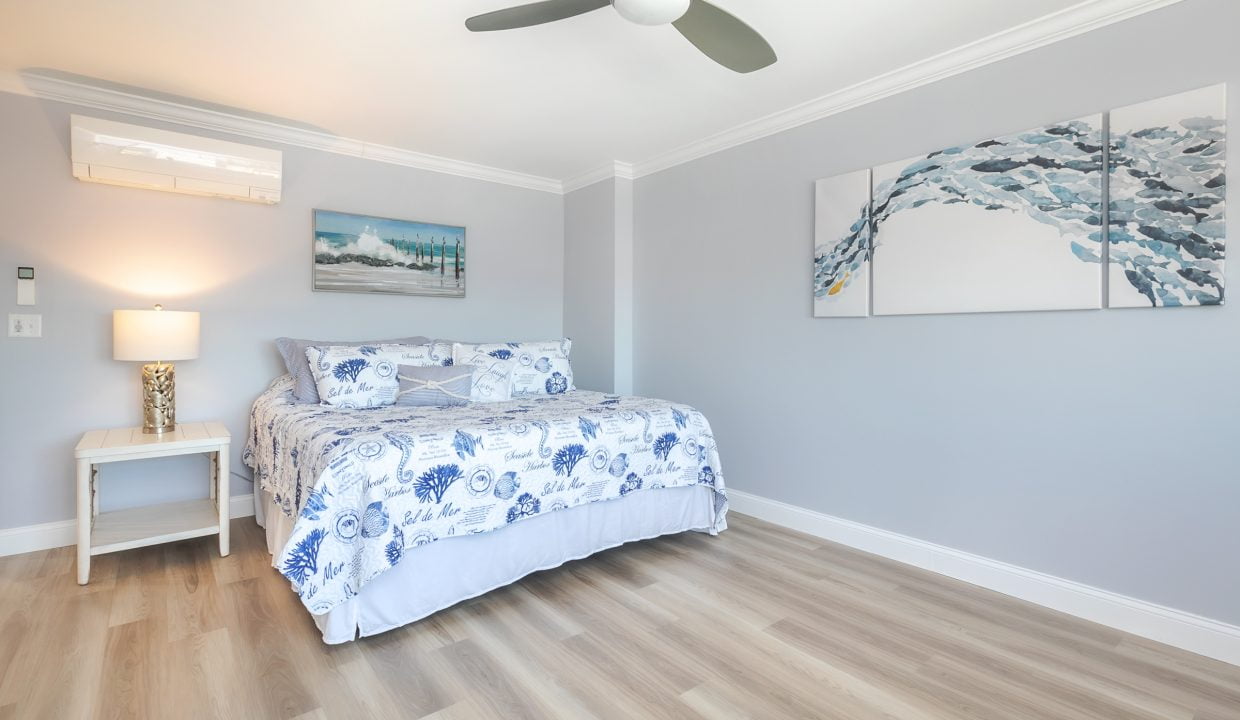 A bedroom with hardwood floors and a ceiling fan.