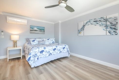 A bedroom with hardwood floors and a ceiling fan.