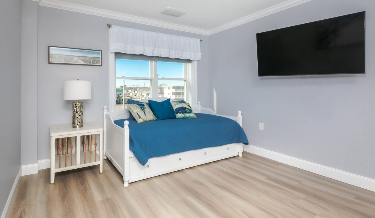 A bedroom with a blue comforter and a tv.