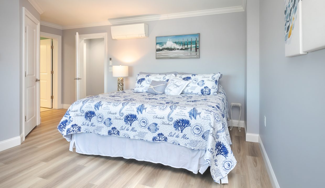 A bedroom with hardwood floors and a blue and white comforter.