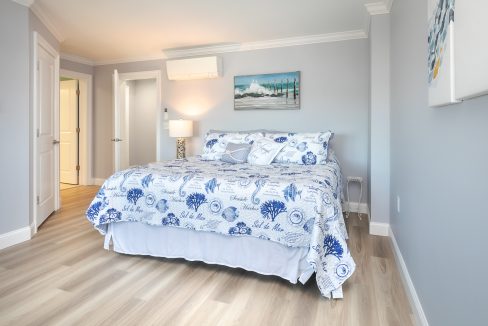 A bedroom with hardwood floors and a blue and white comforter.