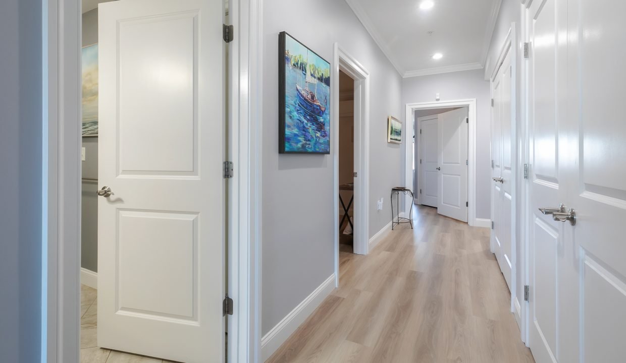A hallway with white doors and a painting on the wall.