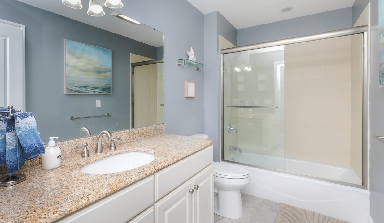 A bathroom with granite counter tops and a walk in shower.