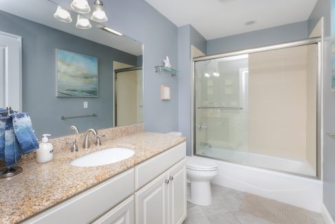A bathroom with granite counter tops and a walk in shower.