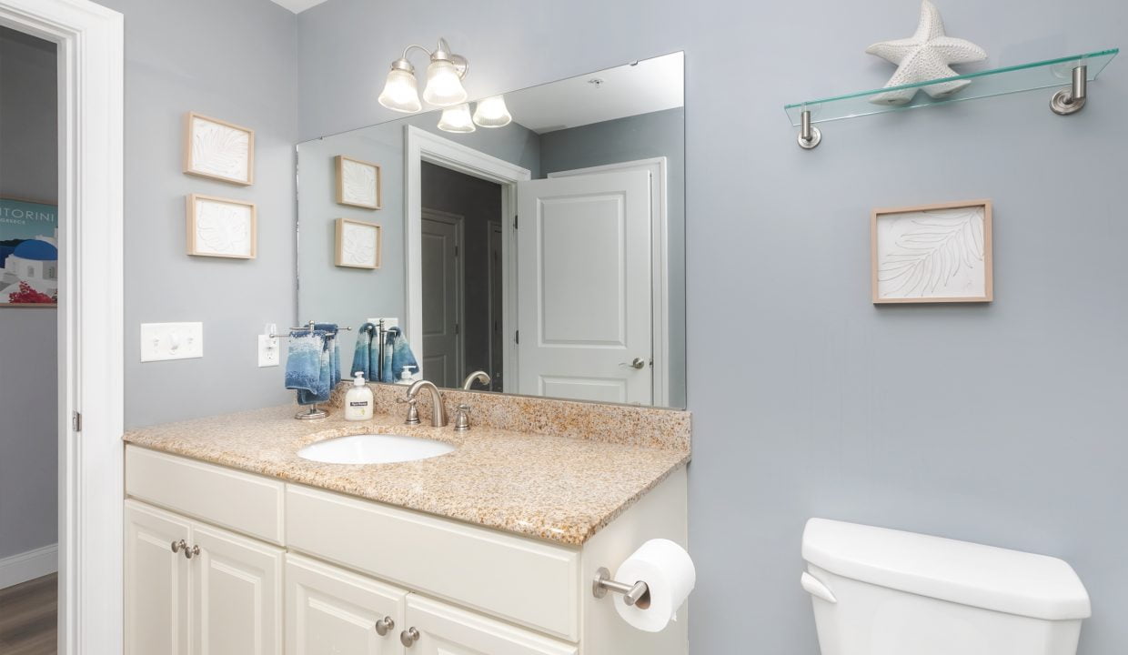 A bathroom with a toilet, sink and mirror.