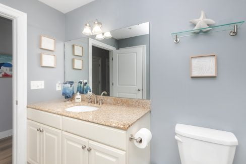 A bathroom with a toilet, sink and mirror.