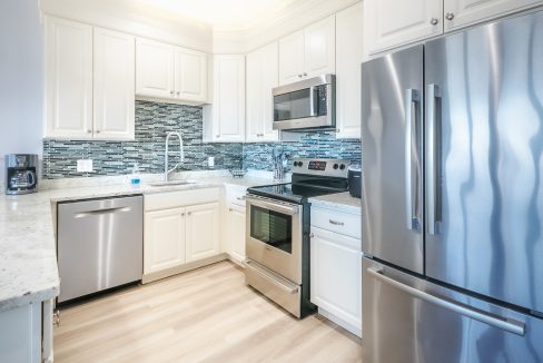 A kitchen with stainless steel appliances and white cabinets.