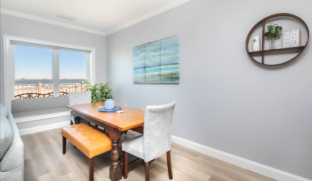 A living room with a table and chairs and a view of the ocean.