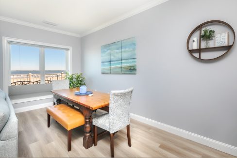 A living room with a table and chairs and a view of the ocean.