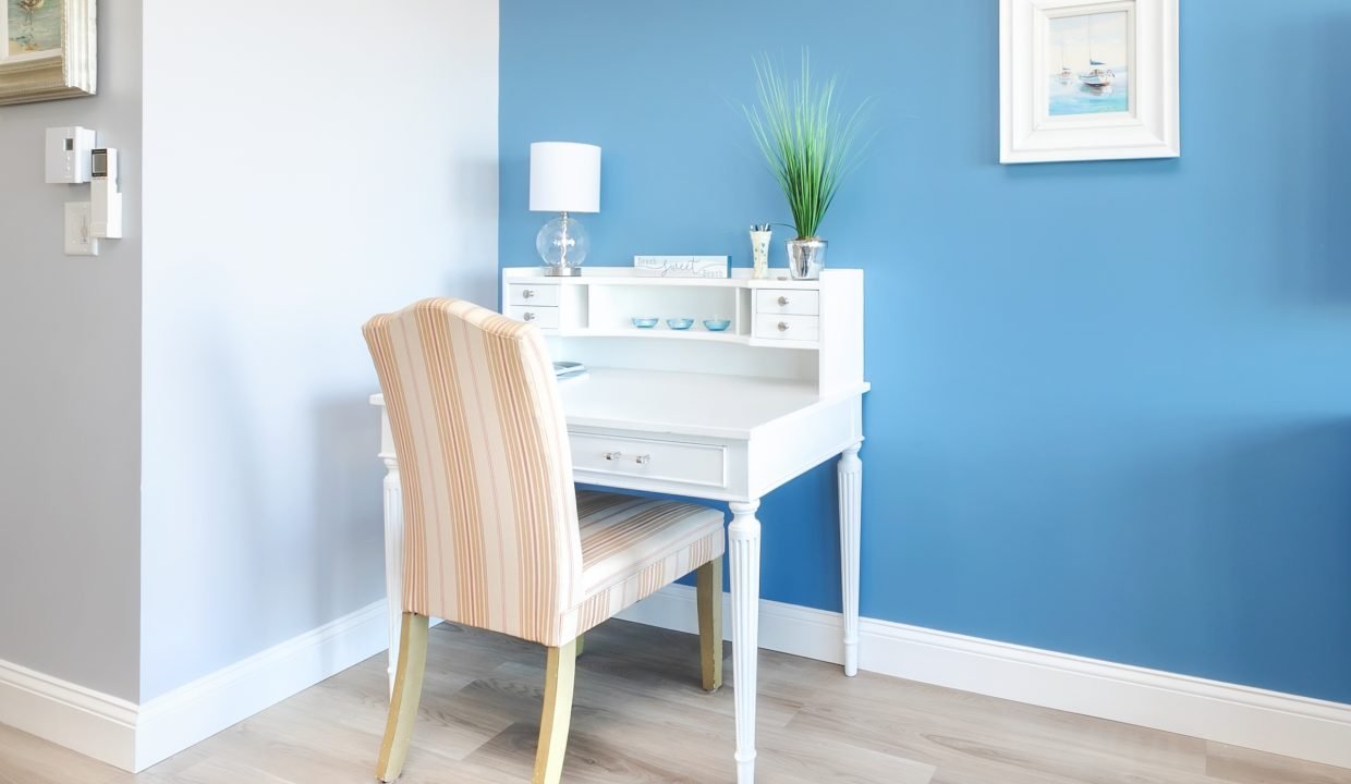 A blue bedroom with a white desk and chair.