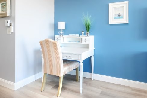 A blue bedroom with a white desk and chair.