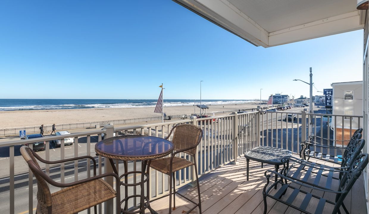 A balcony with a table and chairs overlooking the beach.