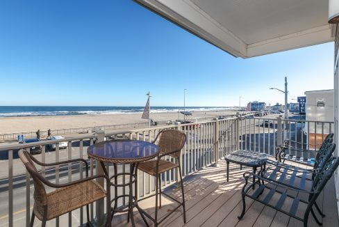 A balcony with a table and chairs overlooking the beach.