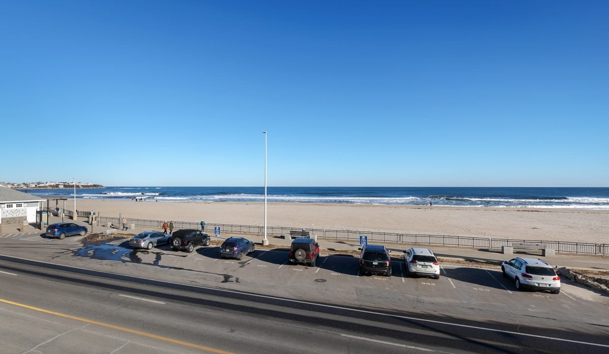 A view of a parking lot with cars parked next to the beach.