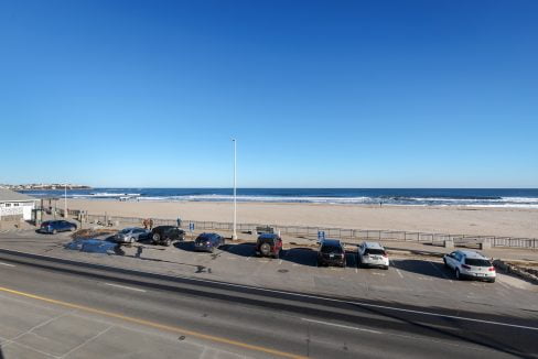 A view of a parking lot with cars parked next to the beach.