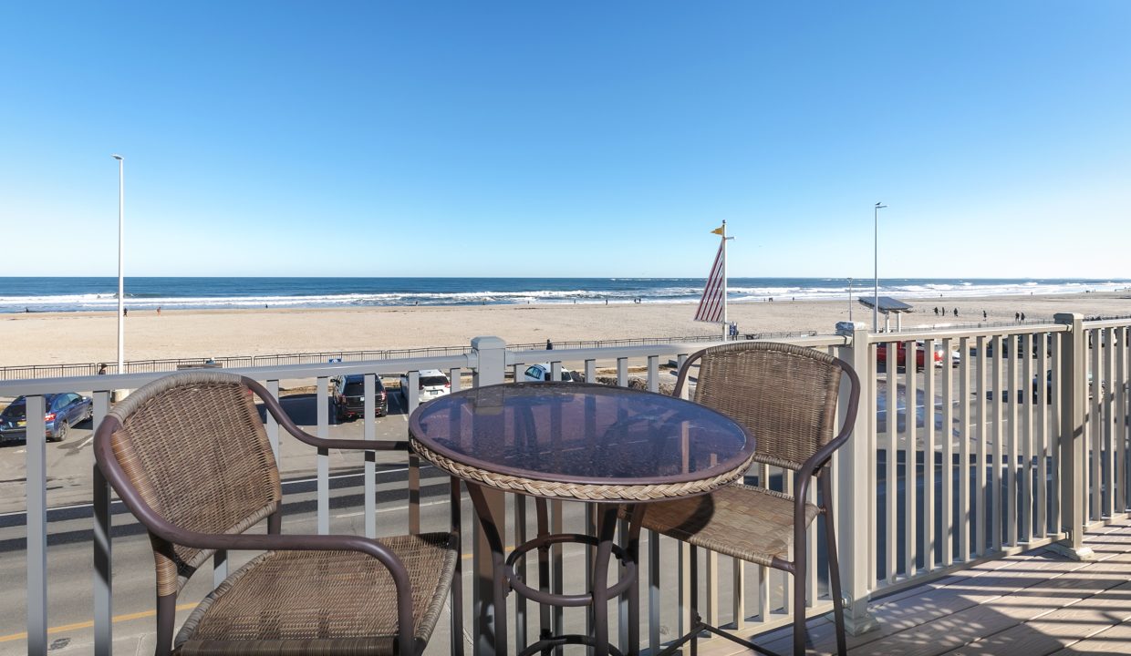 A balcony with a table and chairs overlooking the ocean.