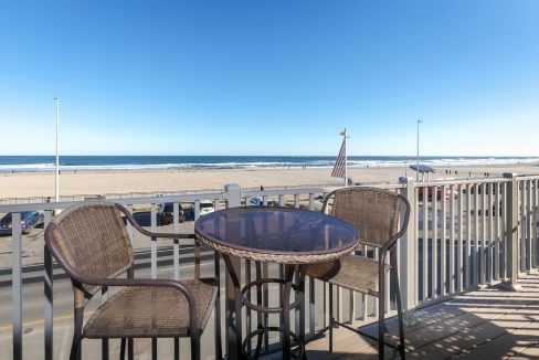 A balcony with a table and chairs overlooking the ocean.