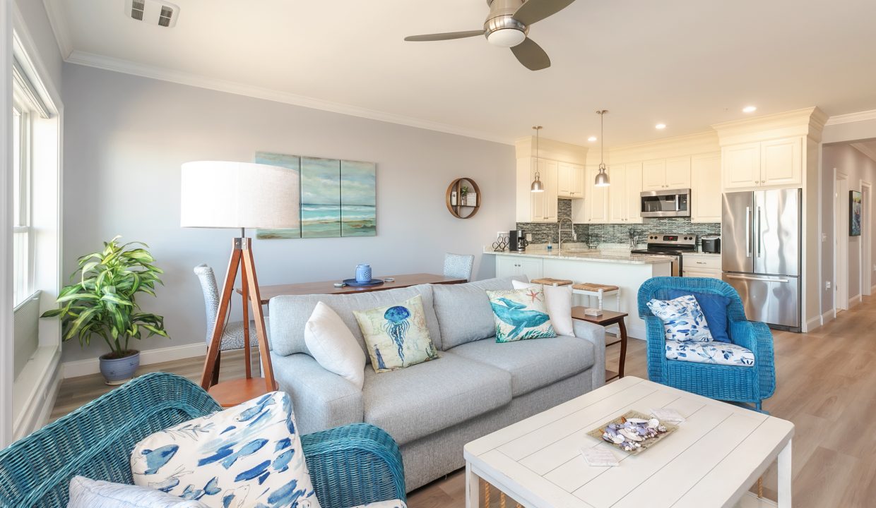 A living room with blue furniture and a ceiling fan.