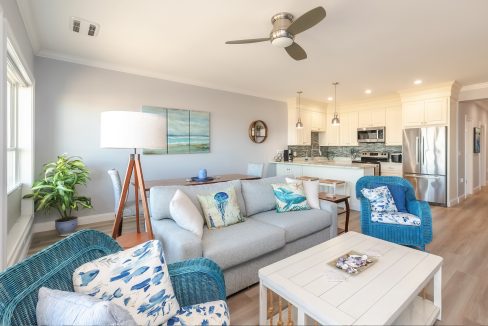 A living room with blue furniture and a ceiling fan.