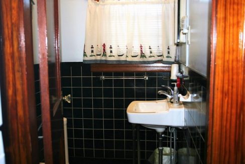 A bathroom with a sink and black tiled walls.