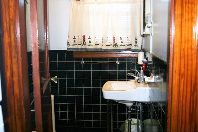 A bathroom with a sink and black tiled walls.