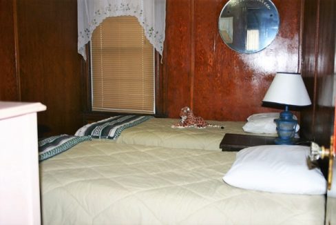 Two beds in a room with wood paneling.